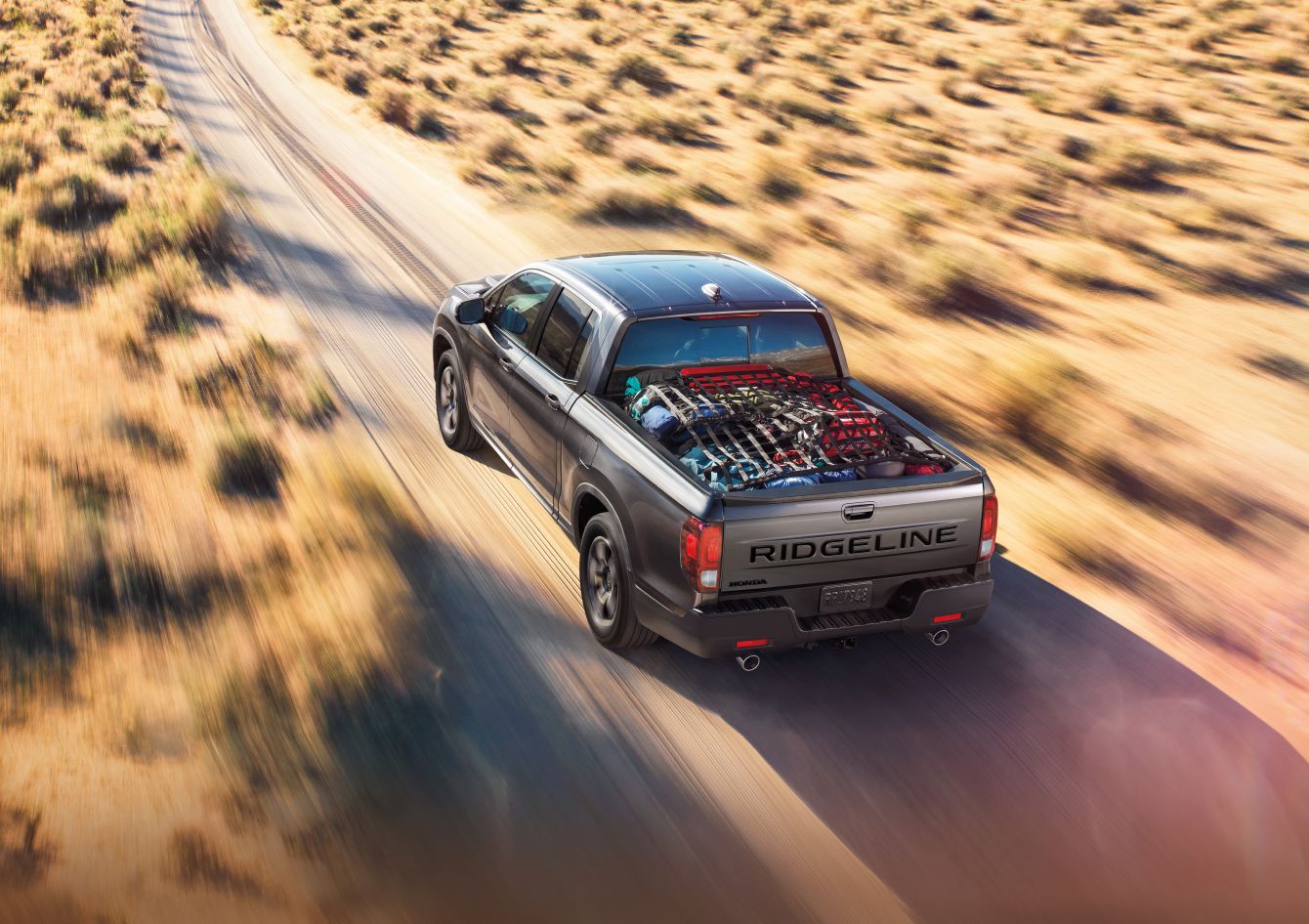 2025 Honda Ridgeline driving down the road with cargo under net