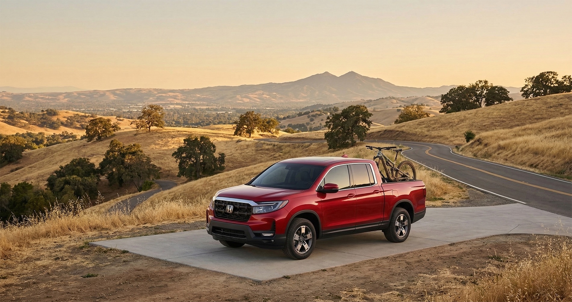 Red Honda Ridgeline pickup parked on a scenic hillside road with golden California hills in the background.