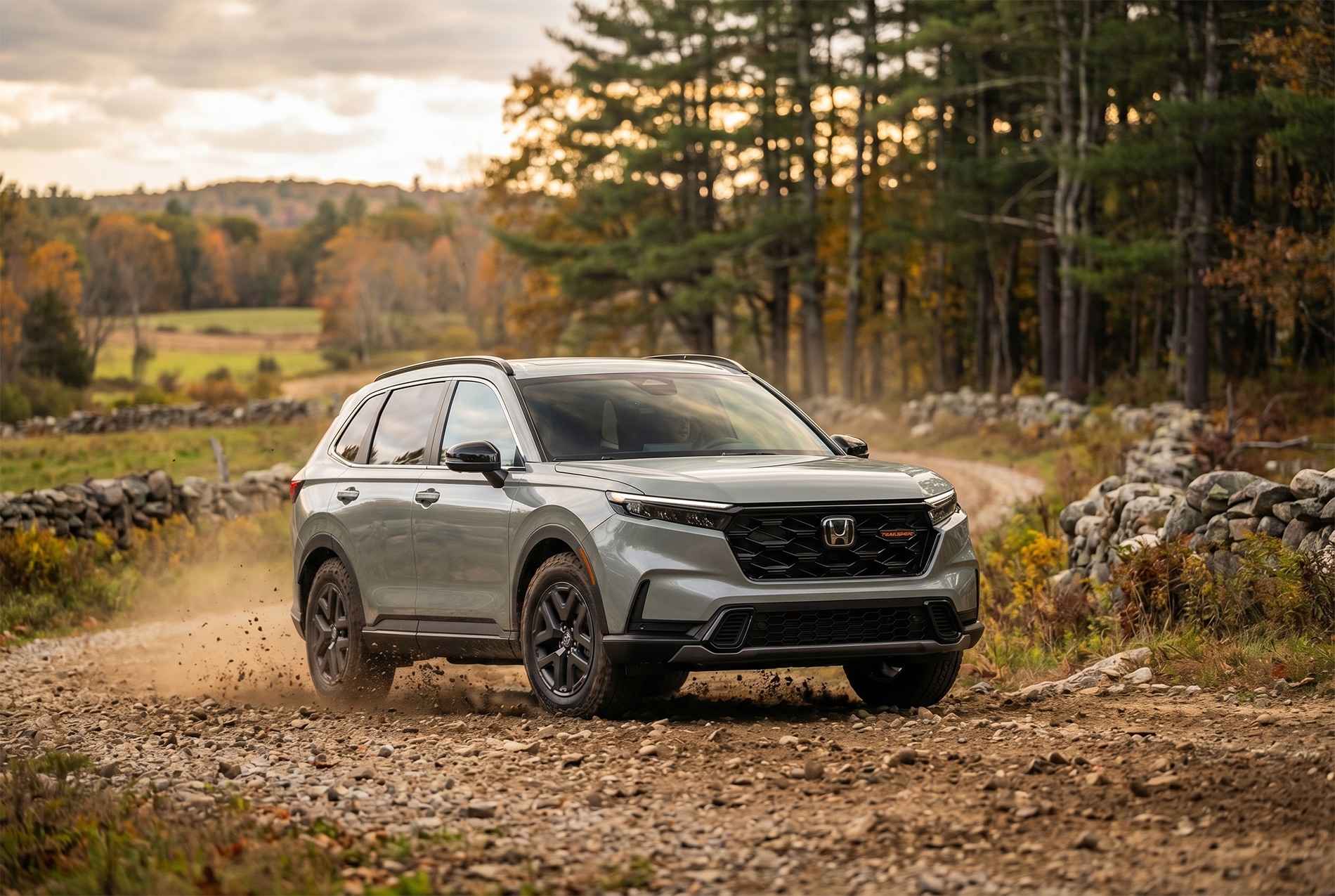 2026 Honda CR-V TrailSport trim level driving on a New England Dirt Road with rock stacked walls and forests