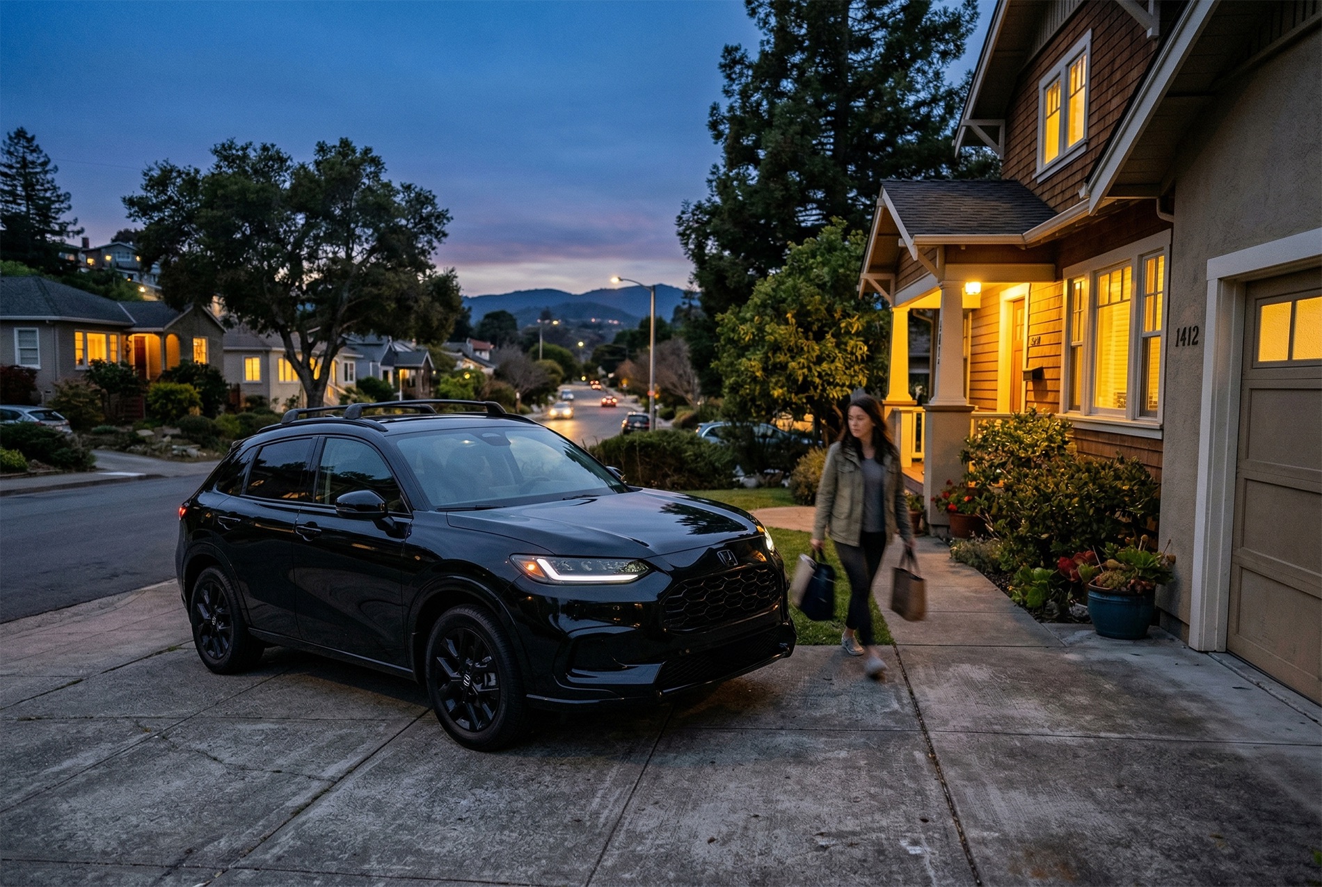 2027 Honda HR‑V parked in the driveway of an El Cerrito home at dusk, with warm house lights glowing and a person carrying shopping bags toward the front door.