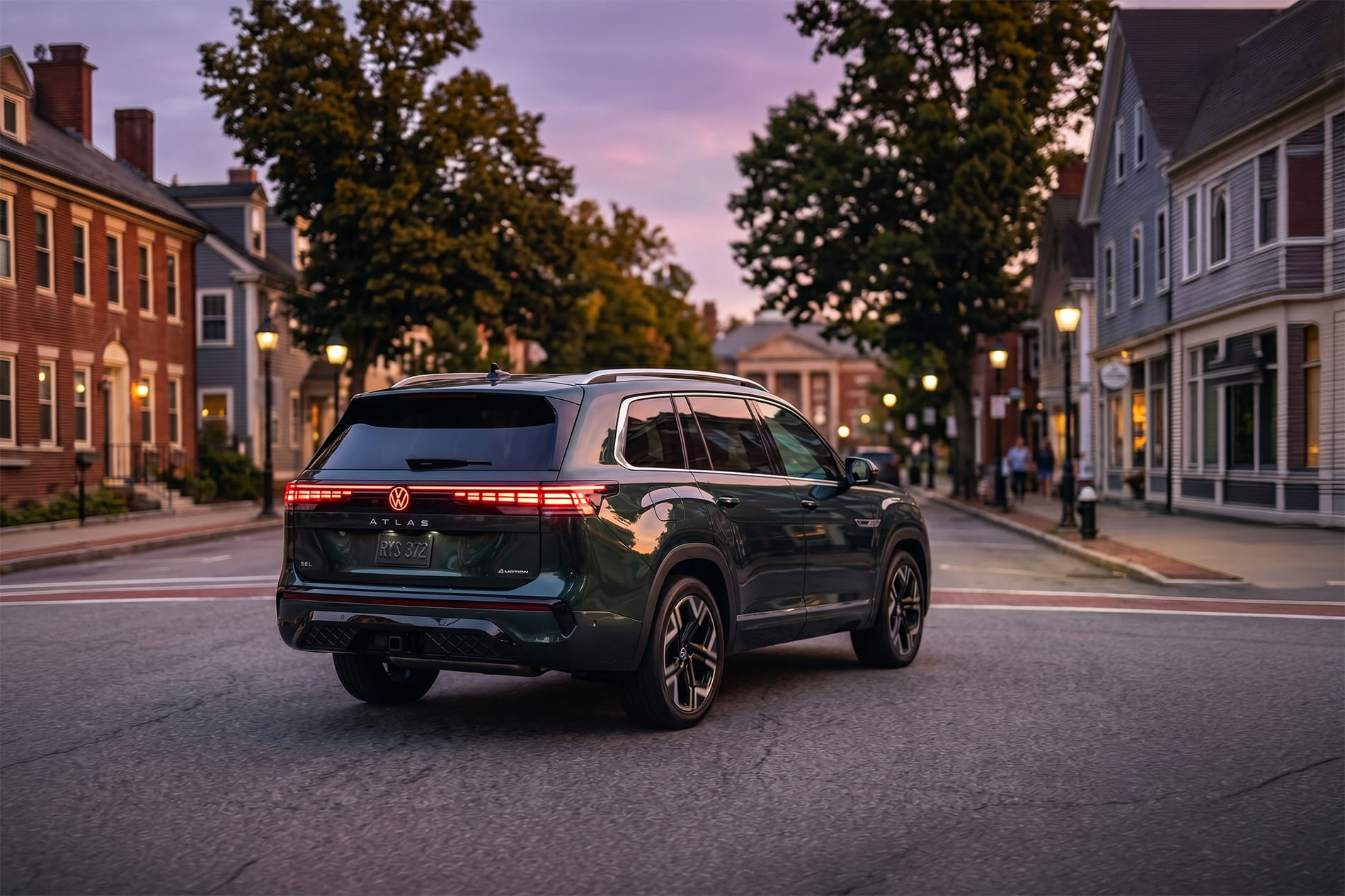 2027 Volkswagen Atlas driving through a small town center at sunset