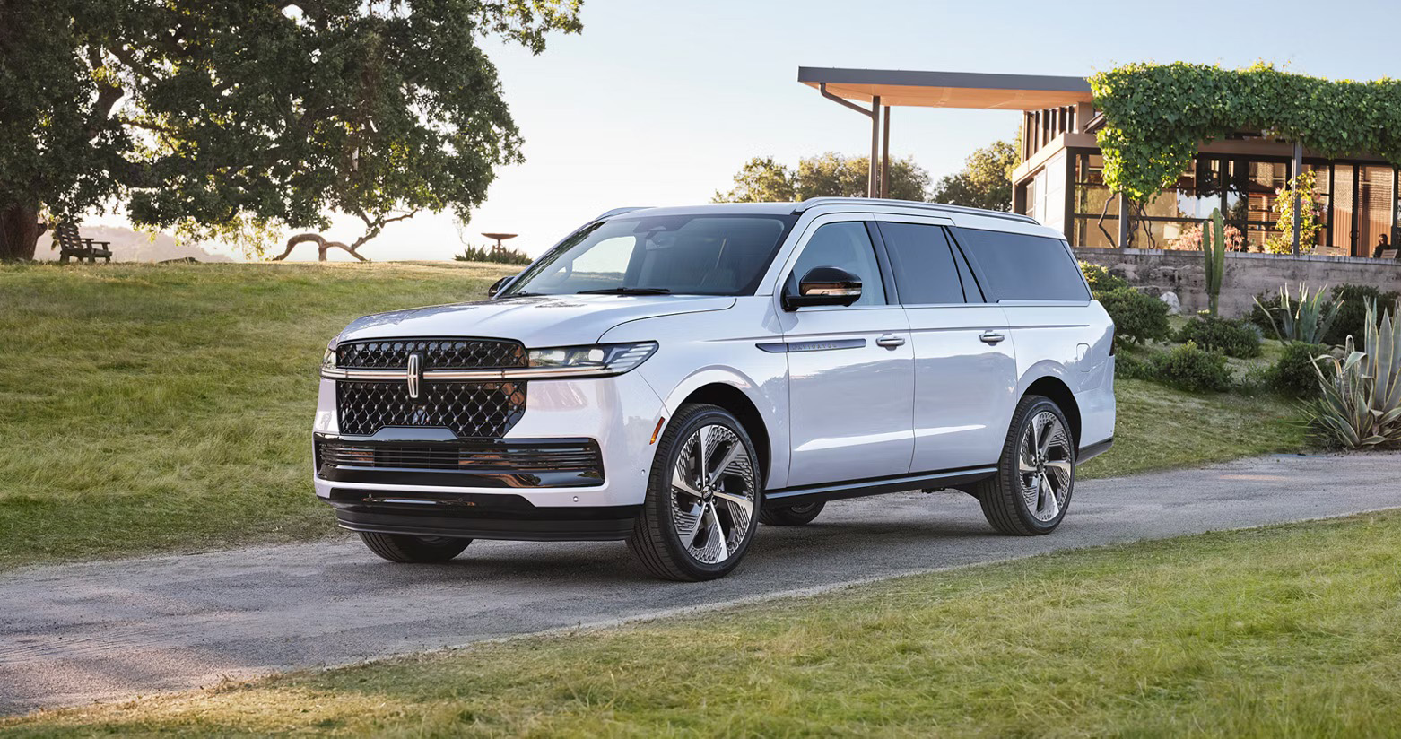 2026 Lincoln Navigator L in white parked on a private estate driveway, shown from a front three-quarter angle with signature grille, large wheels, and upscale full-size luxury SUV design