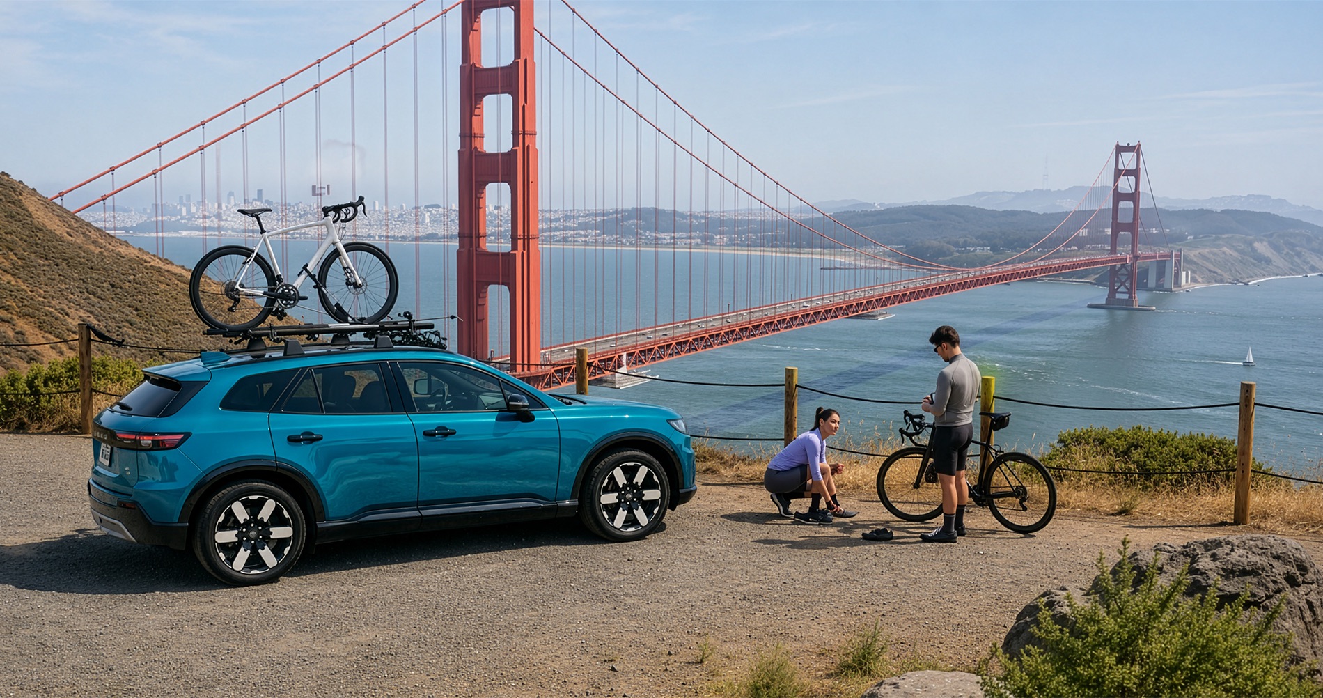 Blue 2026 Honda Prologue parked at a scenic Golden Gate Bridge overlook with two cyclists preparing bikes beside the SUV and a road bike mounted on the roof rack.