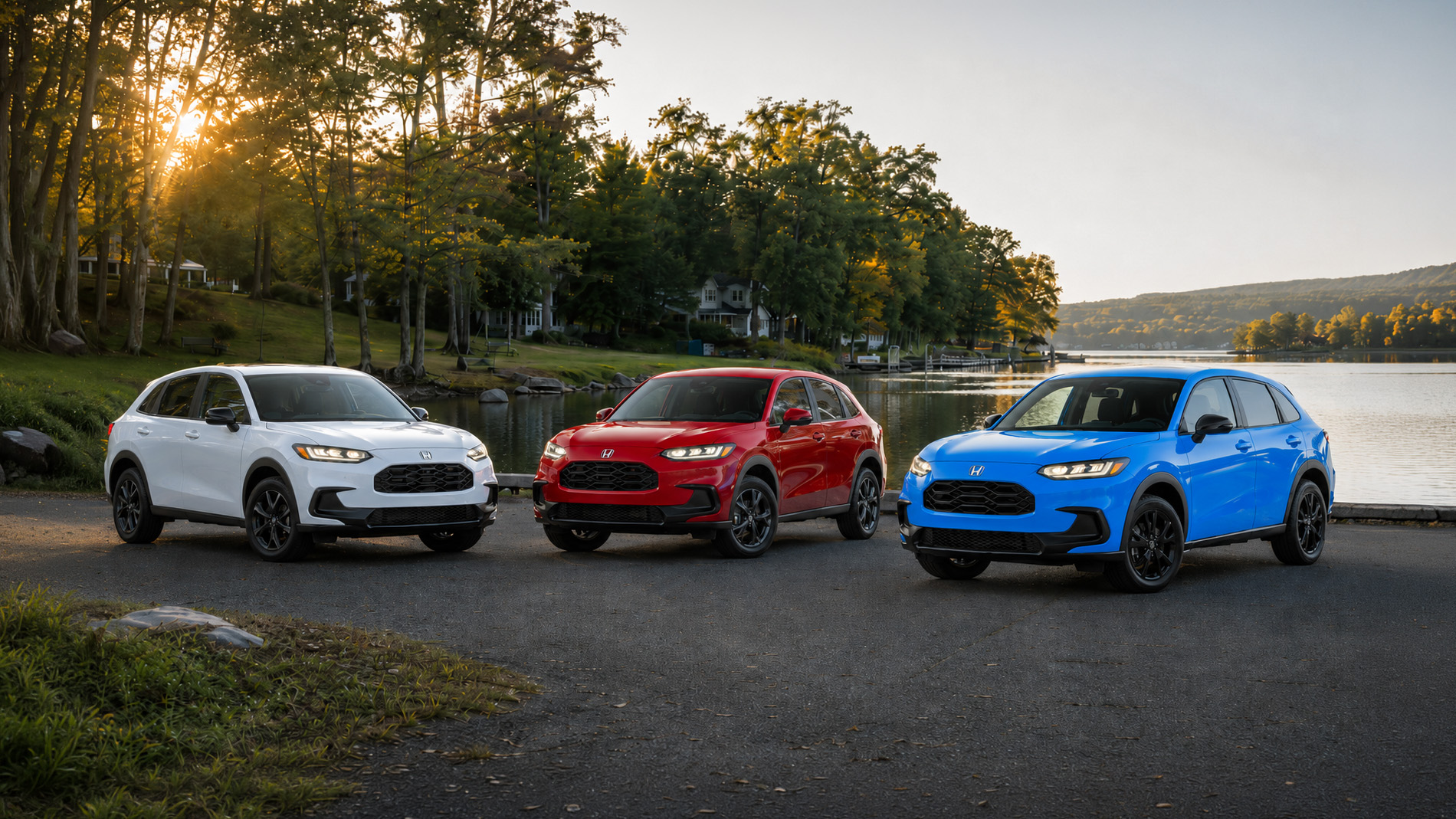 Three 2027 Honda HR-V SUVs in white, red, and blue parked side by side on a lakeside road at sunset, with trees and water in the background, illustrating the SUV’s color range and versatile design for everyday adventure.
