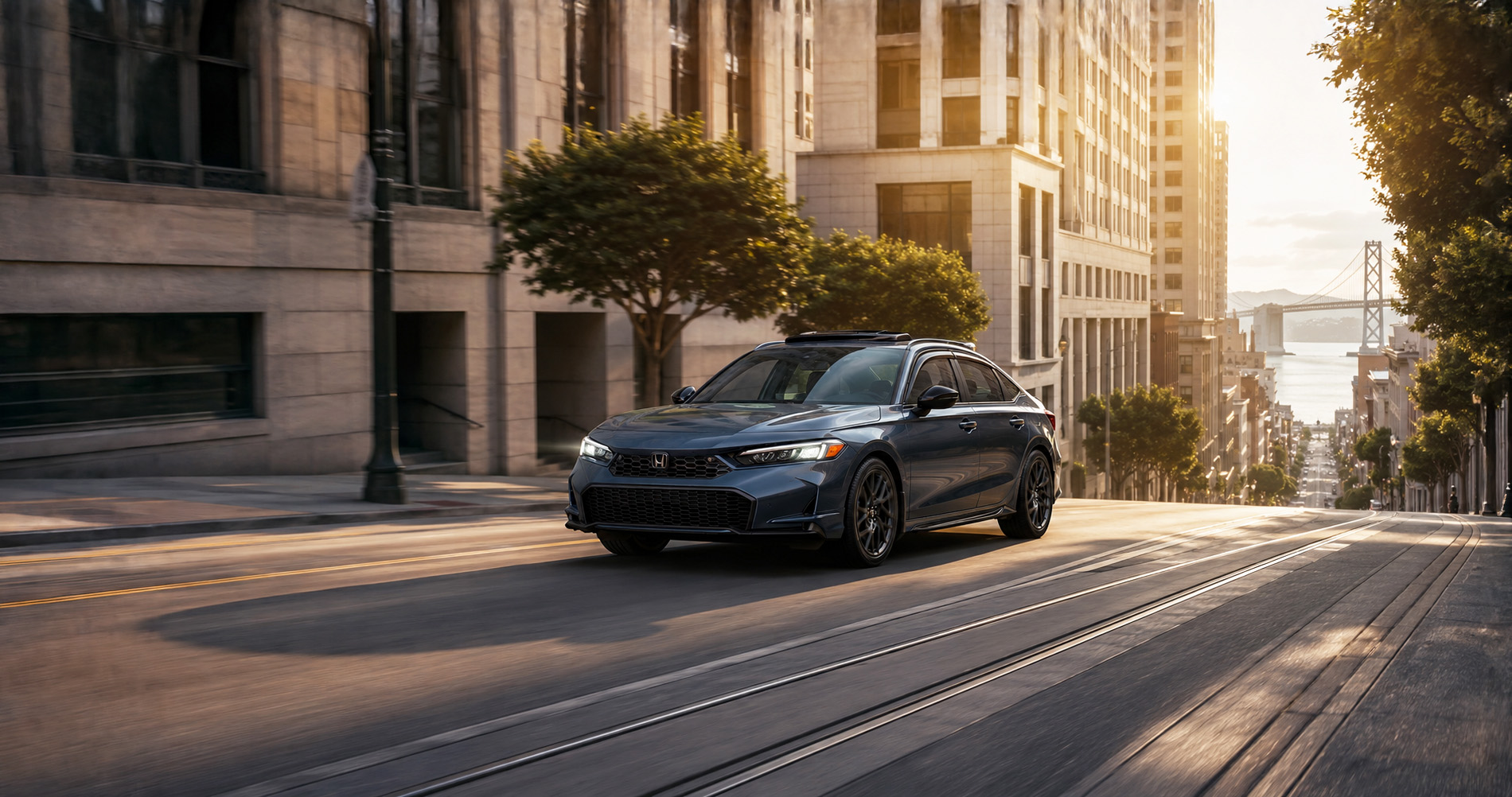 A dark blue Honda Civic sedan fitted with Genuine Honda Accessories drives uphill on a city street lined with tall buildings and trees, with the Bay Bridge visible in the distance under warm evening light, illustrating urban accessories and refined styling.