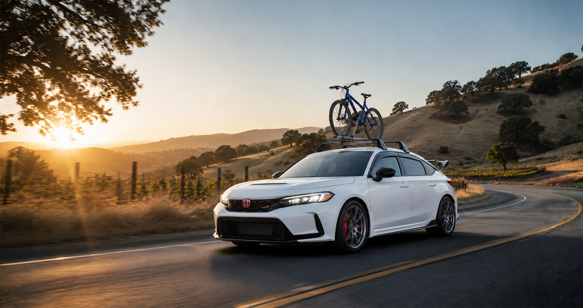 A white Honda Civic Type R equipped with a roof rack and a blue bicycle drives through rolling hills at sunset near Tracy, California, with golden light filtering through trees and fences, showcasing sporty accessories for cycling enthusiasts.
