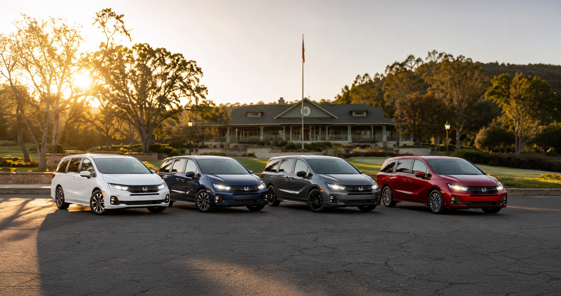 Four 2026 Honda Odyssey minivans in white, dark blue, gray, and red parked side by side in front of a clubhouse surrounded by trees and hills at sunset in El Cerrito, California, illustrating the full range of Odyssey trim levels and color options.