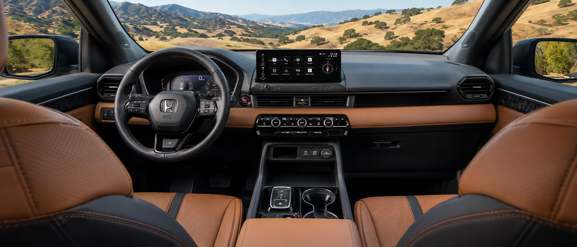 The interior of a 2026 Honda Passport featuring brown leather seats, black accents, and a large touchscreen display showing navigation and apps, with a scenic view of grassy hills and blue skies visible through the windshield, emphasizing the SUV’s premium craftsmanship and technology.