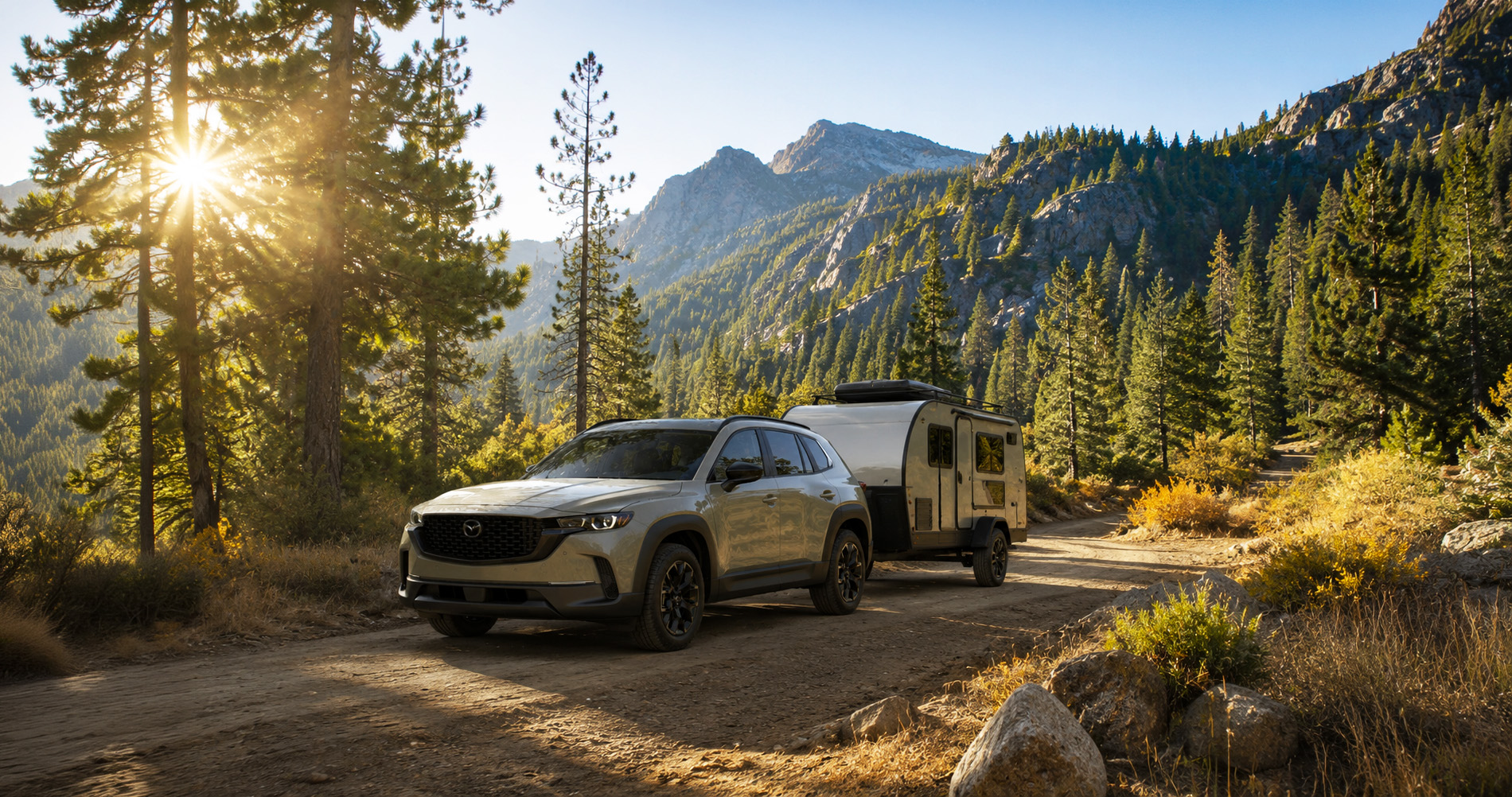 Tan CX-50 towing a small trailer on a forest road at sunrise, highlighting weekend travel versatility.