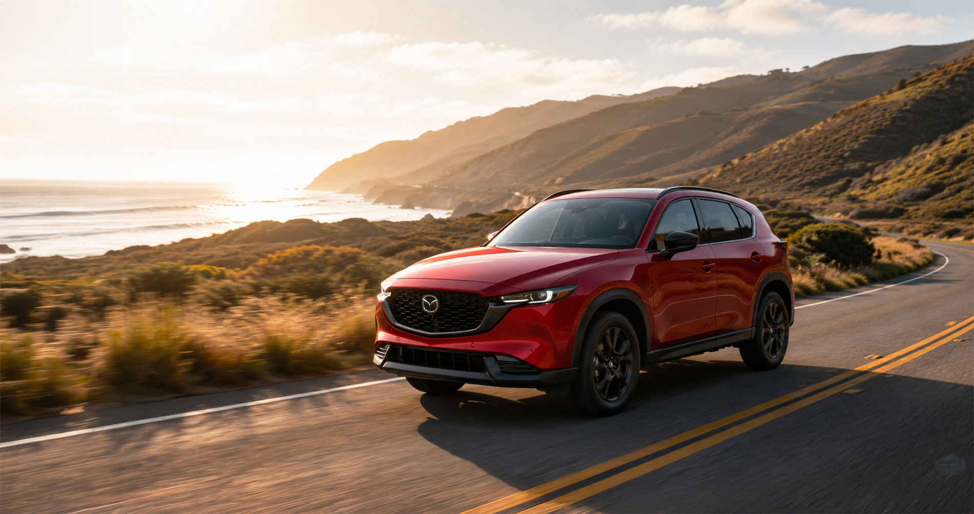 Red CX‑5 driving along a scenic coastal highway at sunset, emphasizing performance and elegance.