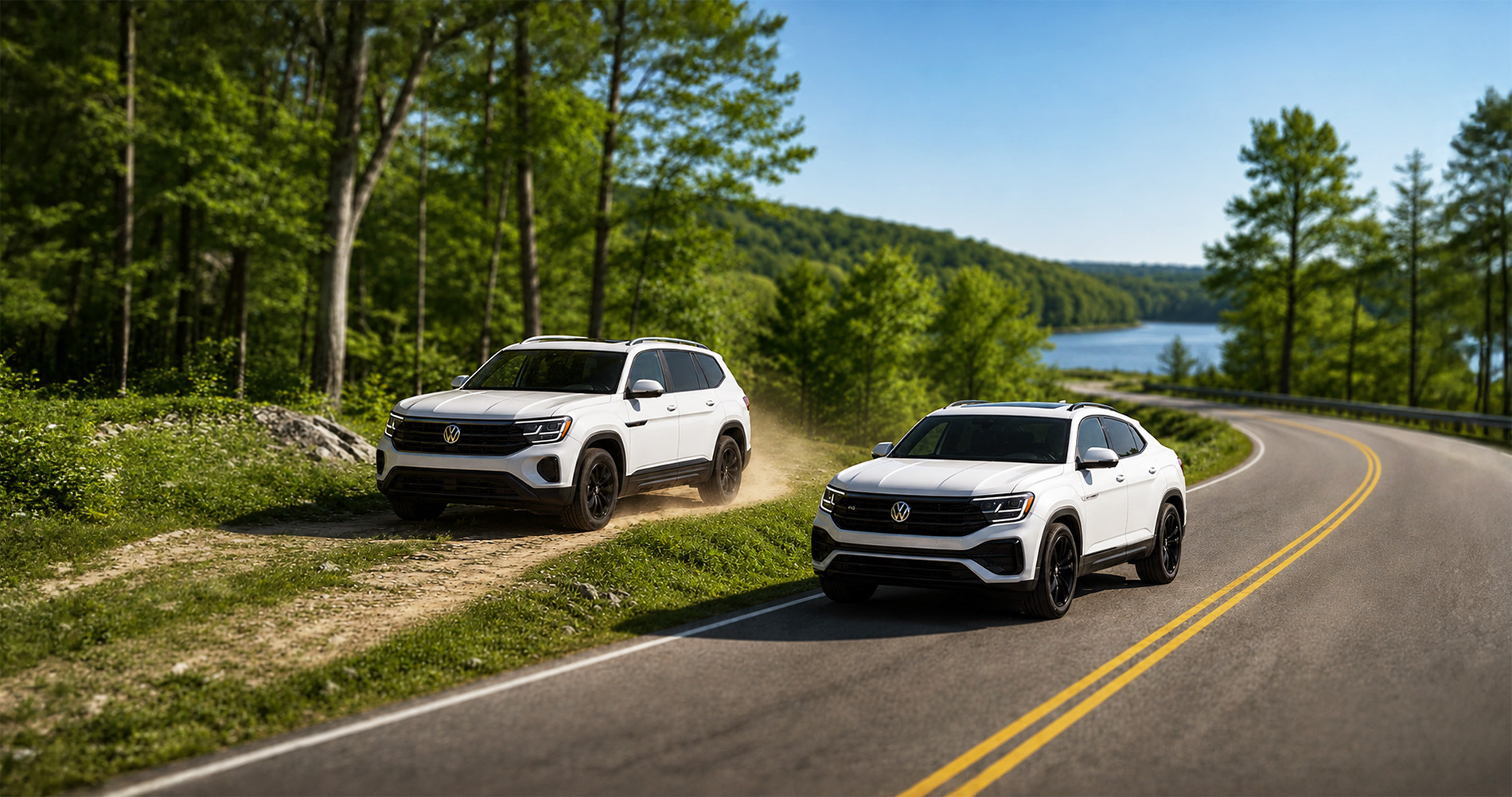 Two white Volkswagen SUVs—a 2026 Atlas and a 2026 Atlas Cross Sport—driving side by side along a winding forest road near Easton, Massachusetts, with one vehicle on pavement and the other on a dirt trail, surrounded by tall green trees and a lake in the background under a clear blue sky.