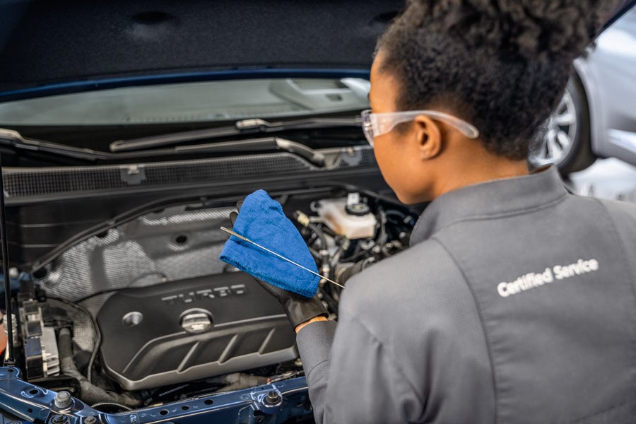 Certified female technician checking oil after an express Chevy service