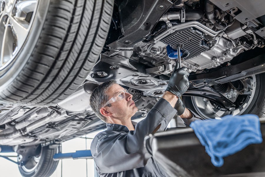 Certified tecnician doing an oil change on a vehicle on a lift