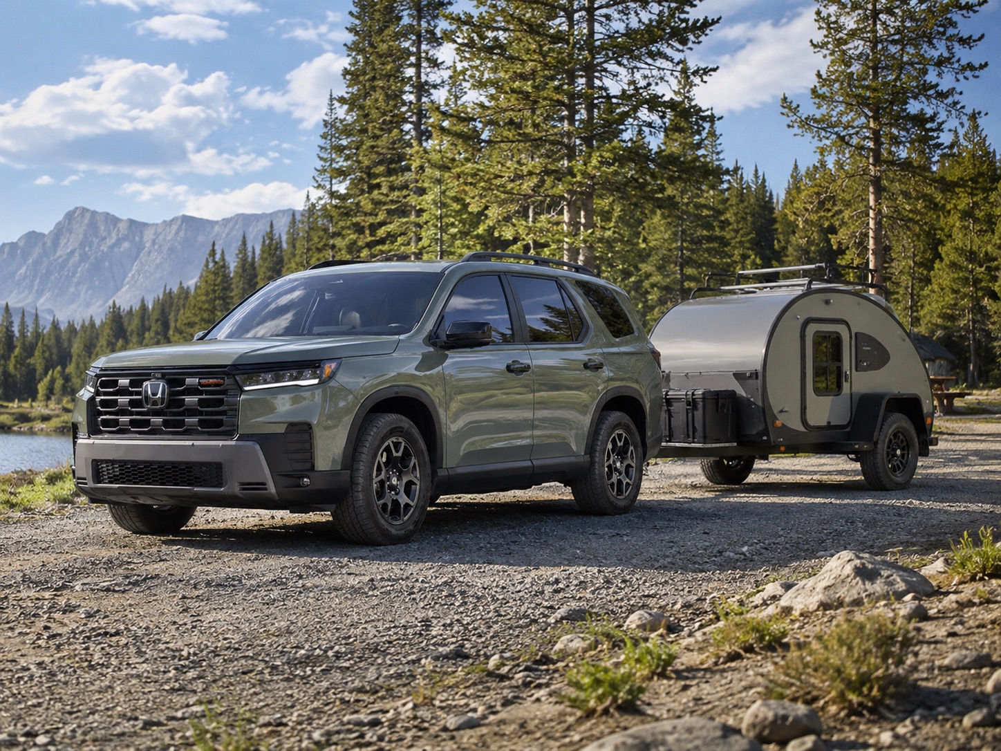 Green 2026 Honda Pilot TrailSport towing a small teardrop camper trailer near a forested lakeside campsite
