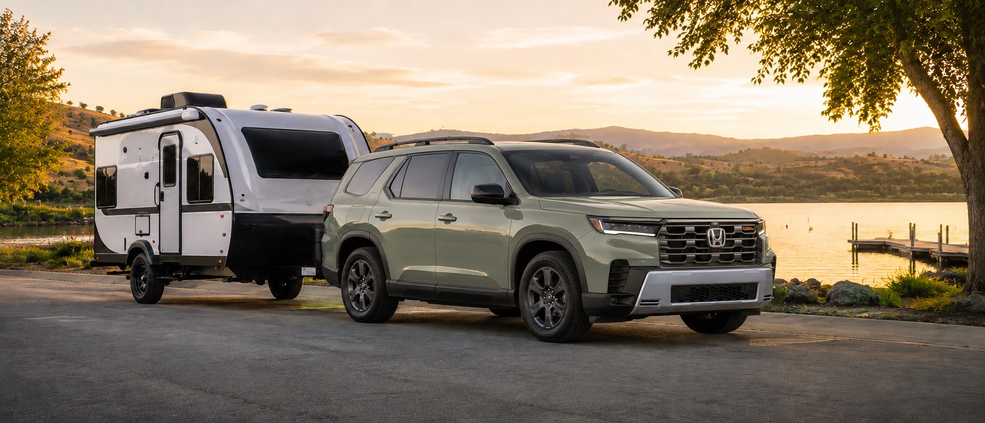 Green 2026 Honda Pilot towing a small travel trailer beside a lakeshore at sunset near Tracy California