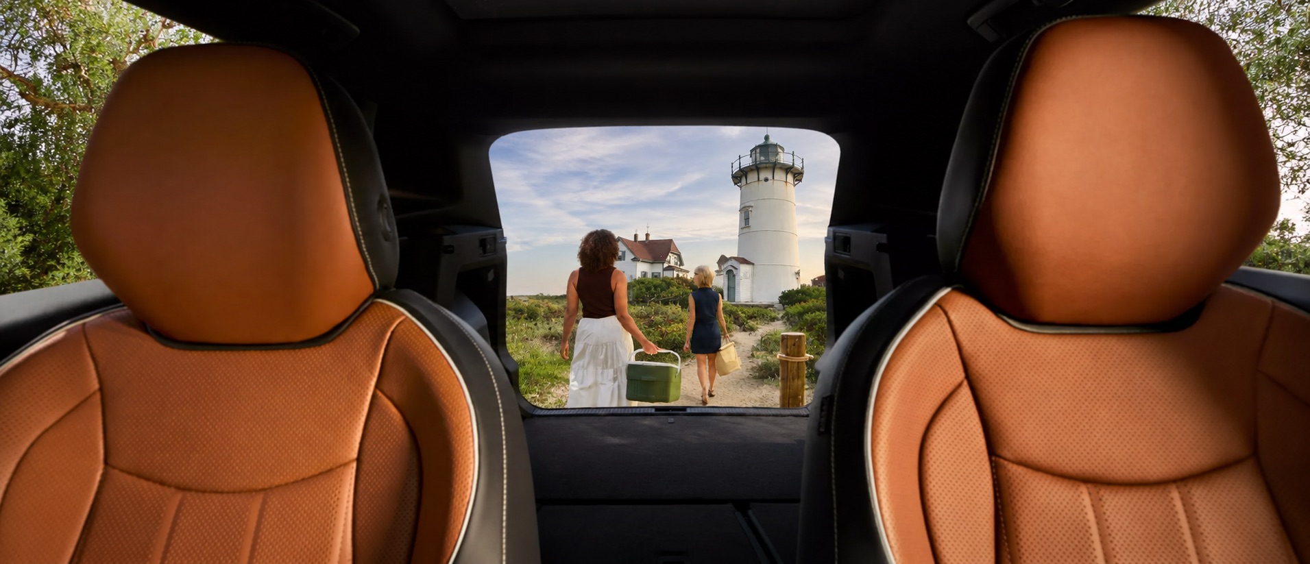 View from inside a Volkswagen Tiguan with amber brown leather seats as two people walk toward a Cape Cod lighthouse through the open rear cargo area.
