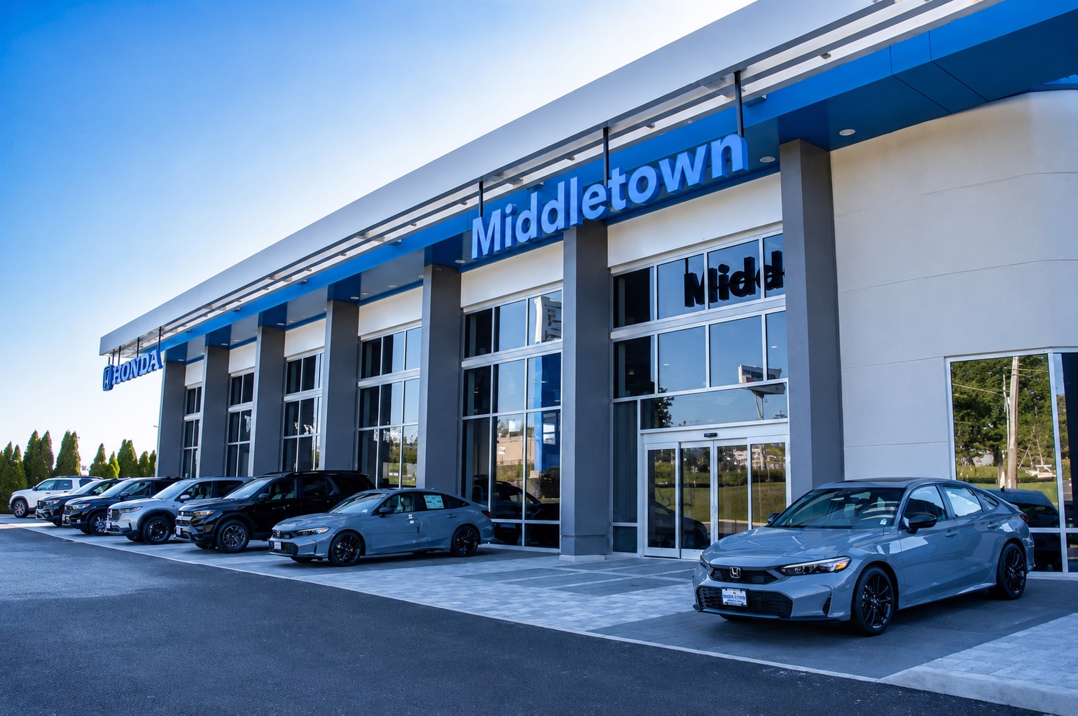Exterior view of the Middletown Honda dealership showroom with Honda vehicles parked outside under a clear blue sky