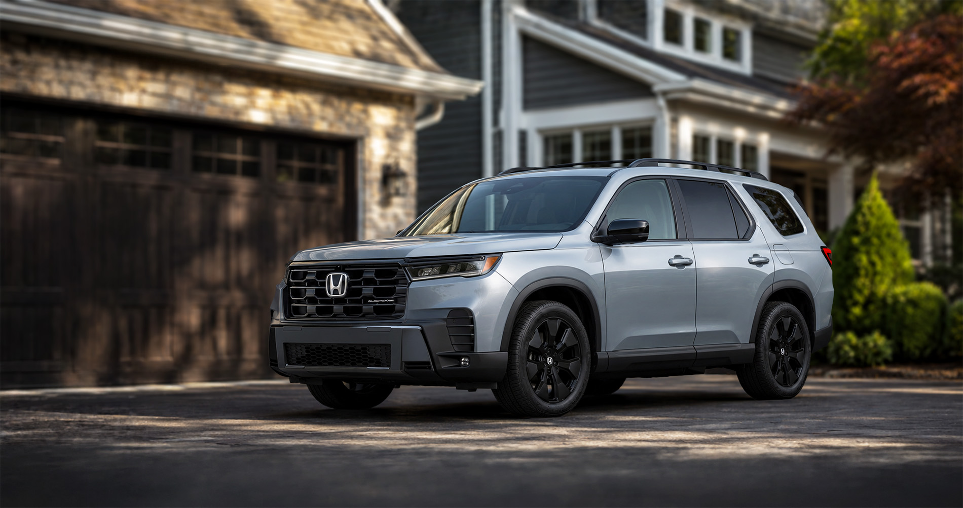 Silver Honda Pilot Black Edition parked in driveway at sunrise highlighting black wheels and bold front grille.