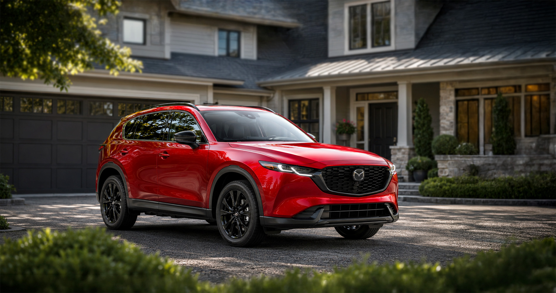 Red Mazda CX‑5 SUV parked in driveway at sunrise highlighting sleek styling and black alloy wheels.