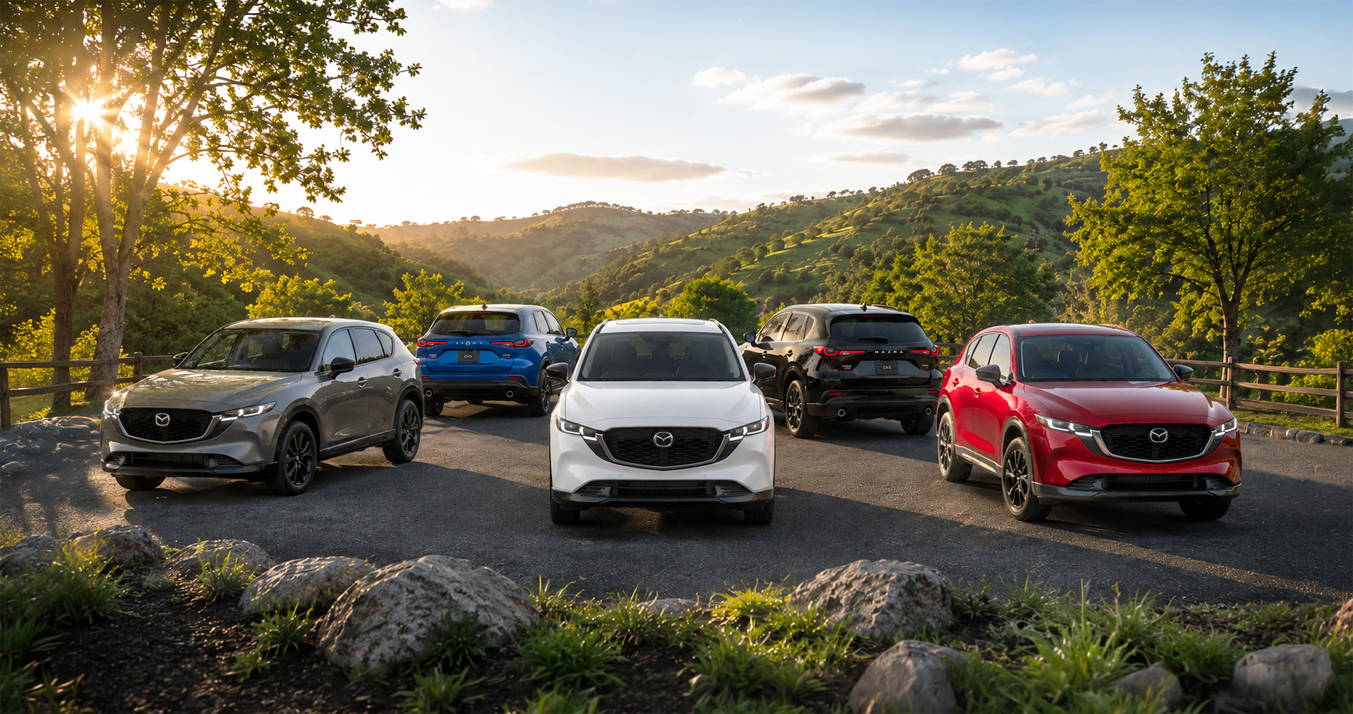 Five Mazda CX‑5 SUVs in gray blue white black and red parked on hilltop at sunset showcasing full trim range.