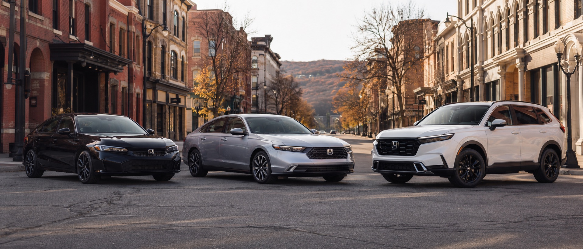 Black 2026 Honda Civic Touring Hybrid, silver 2026 Honda Accord Touring Hybrid, and white 2026 Honda CR-V Touring Hybrid parked along a downtown Middletown, New York street