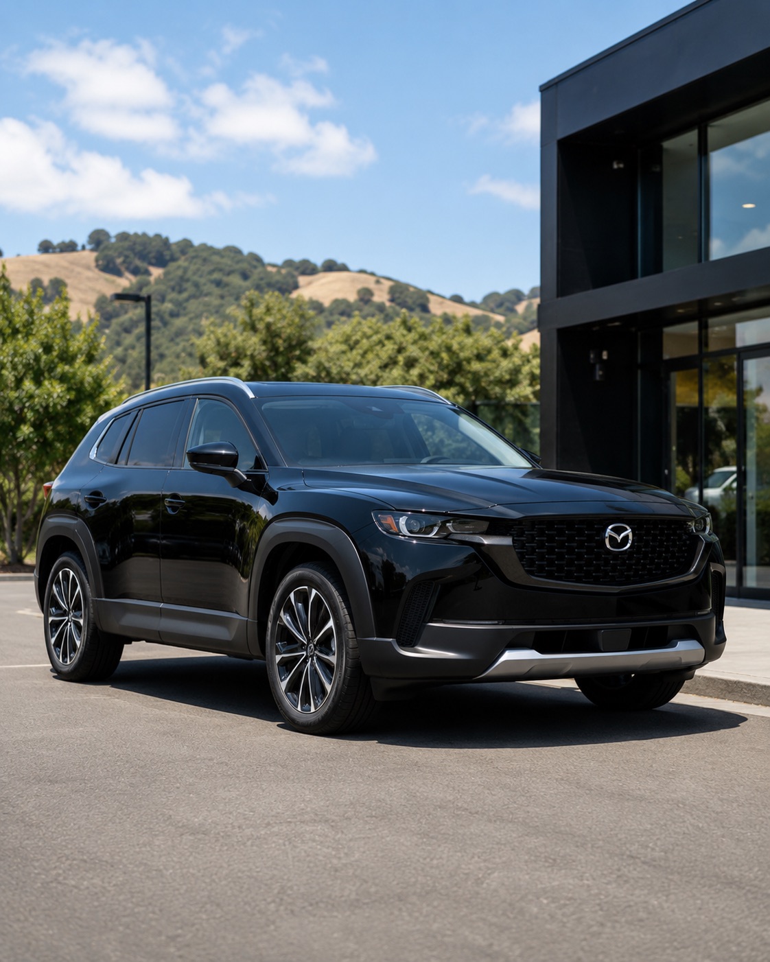 Black 2026 Mazda CX-50 Hybrid parked outside a modern dealership with East Bay hills in the background.