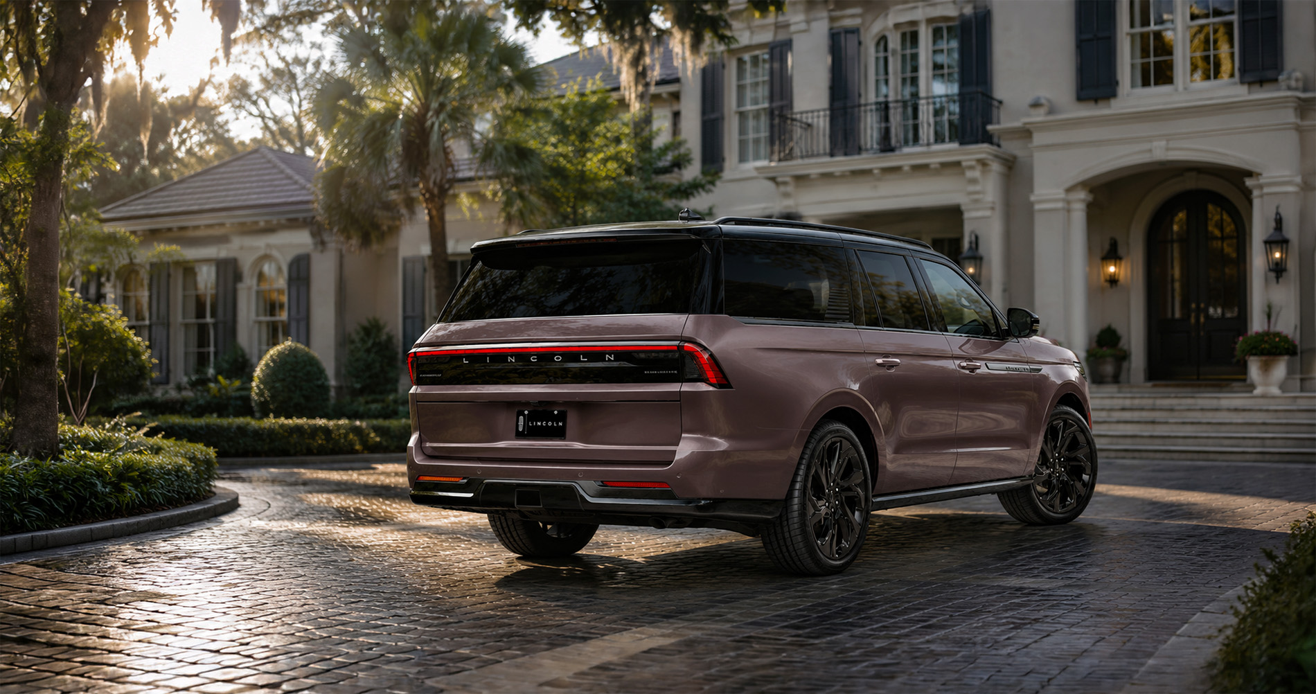 Purple-brown Lincoln Navigator L parked on a cobblestone driveway in front of a luxury home.