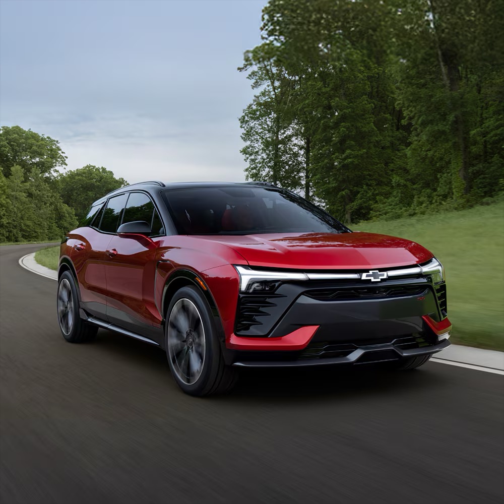 2026 Chevy Blazer EV in red driving down a wooded highway