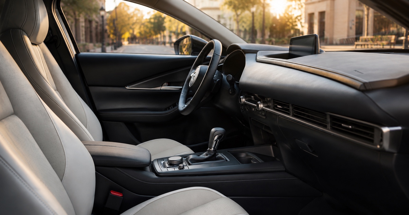 Mazda CX‑30 cabin with light leather seats and black dashboard showing center console gear selector and steering wheel design.
