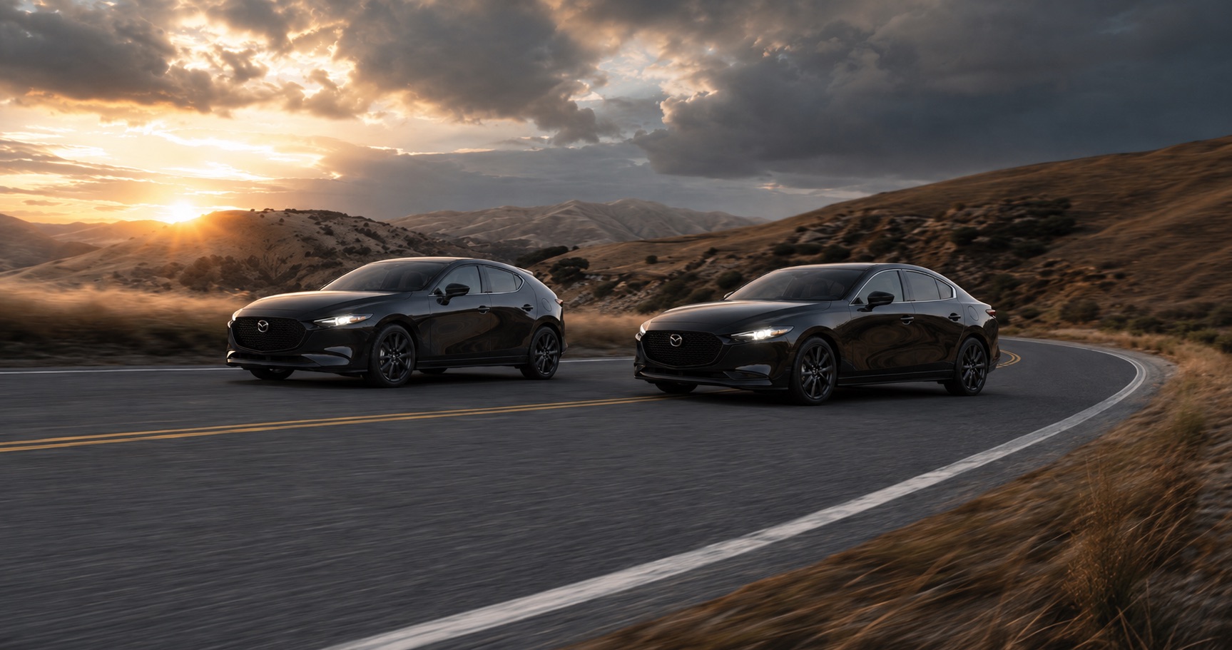 Black Mazda3 hatchback and sedan driving on winding mountain road at sunset showcasing sleek design and performance in golden light.