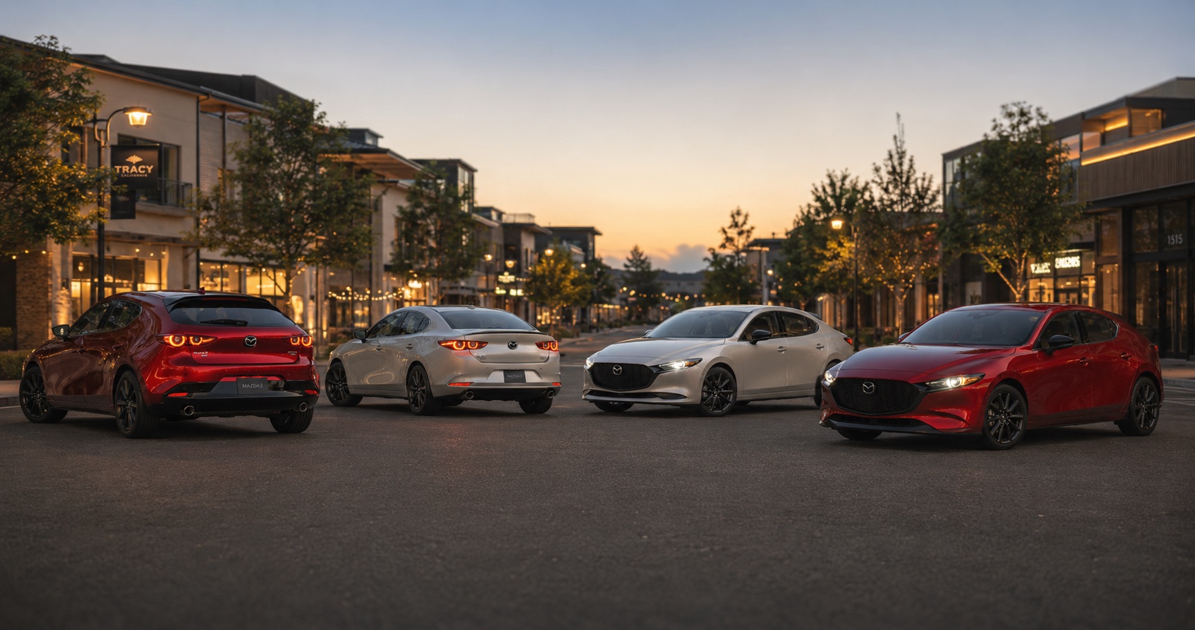 Four Mazda3 models in red white and silver parked on downtown street at sunset near Tracy shops highlighting full trim range and color options.