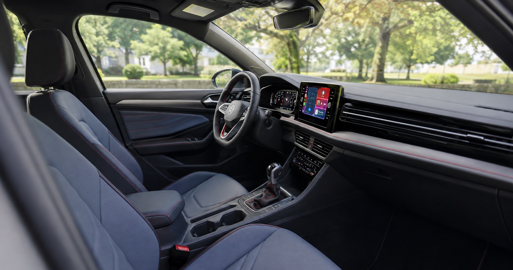2026 VW Jetta GLI cabin view with Titan black dashboard, Grigio with Red Crust color pattern on the seats, digital display and manual transmission.