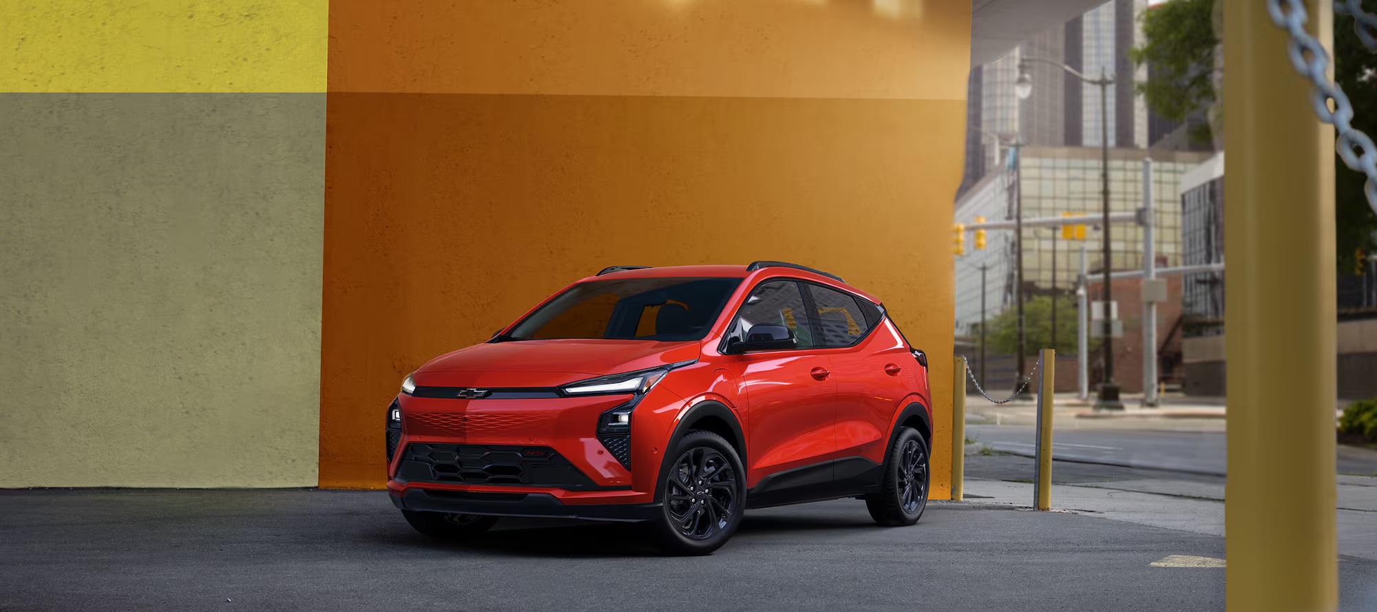 Red 2027 Chevy Bolt RS parked against a modern mural in city