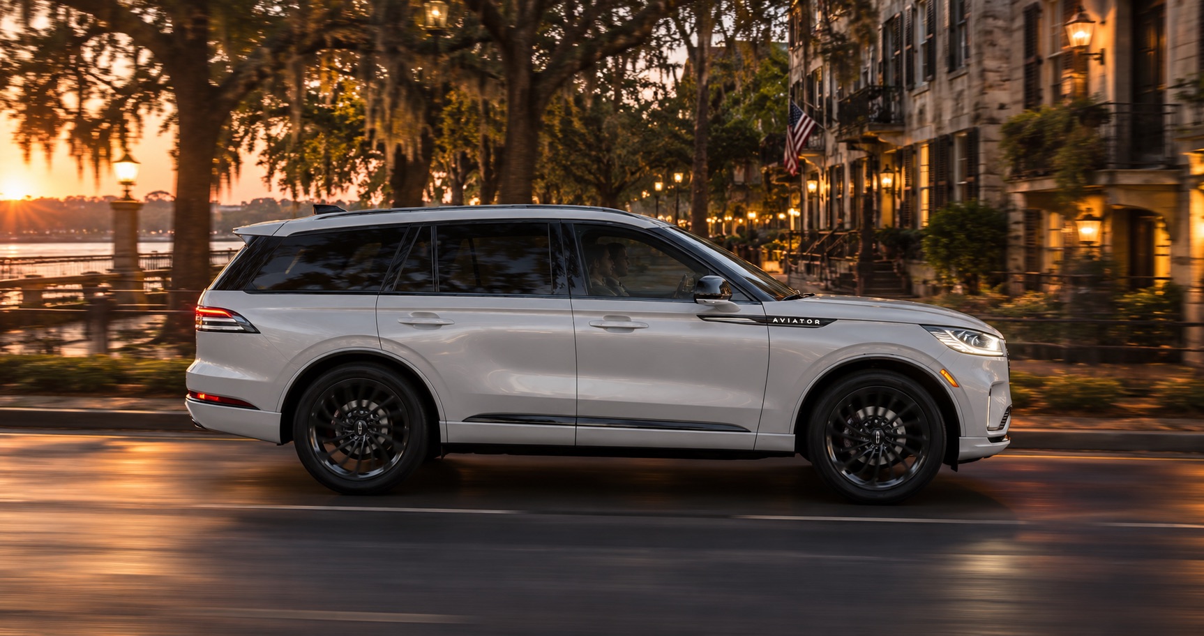 2027 Lincoln Aviator Reserve driving along a tree-lined waterfront street at sunset in Savannah, GA