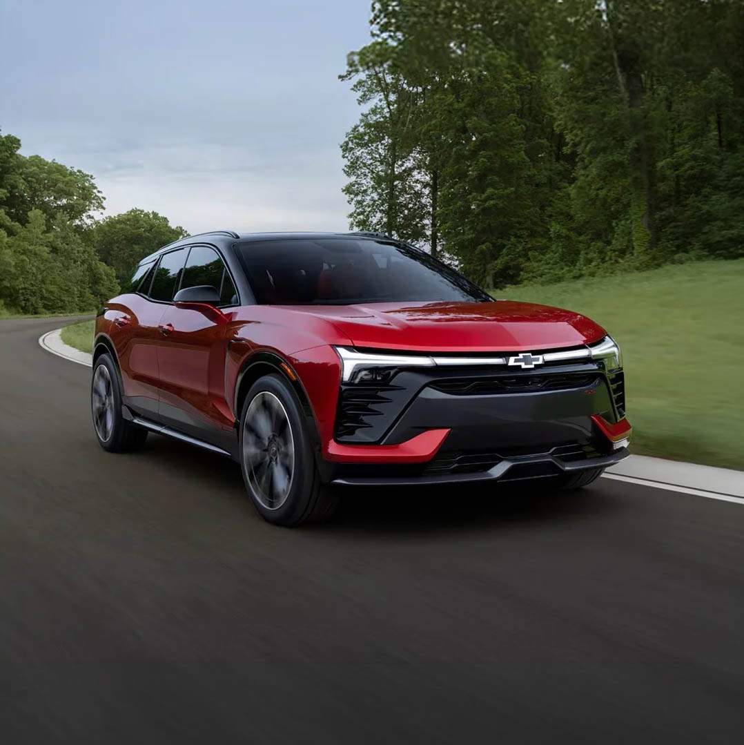 2026 Chevrolet Blazer EV in red driving down a wooded highway