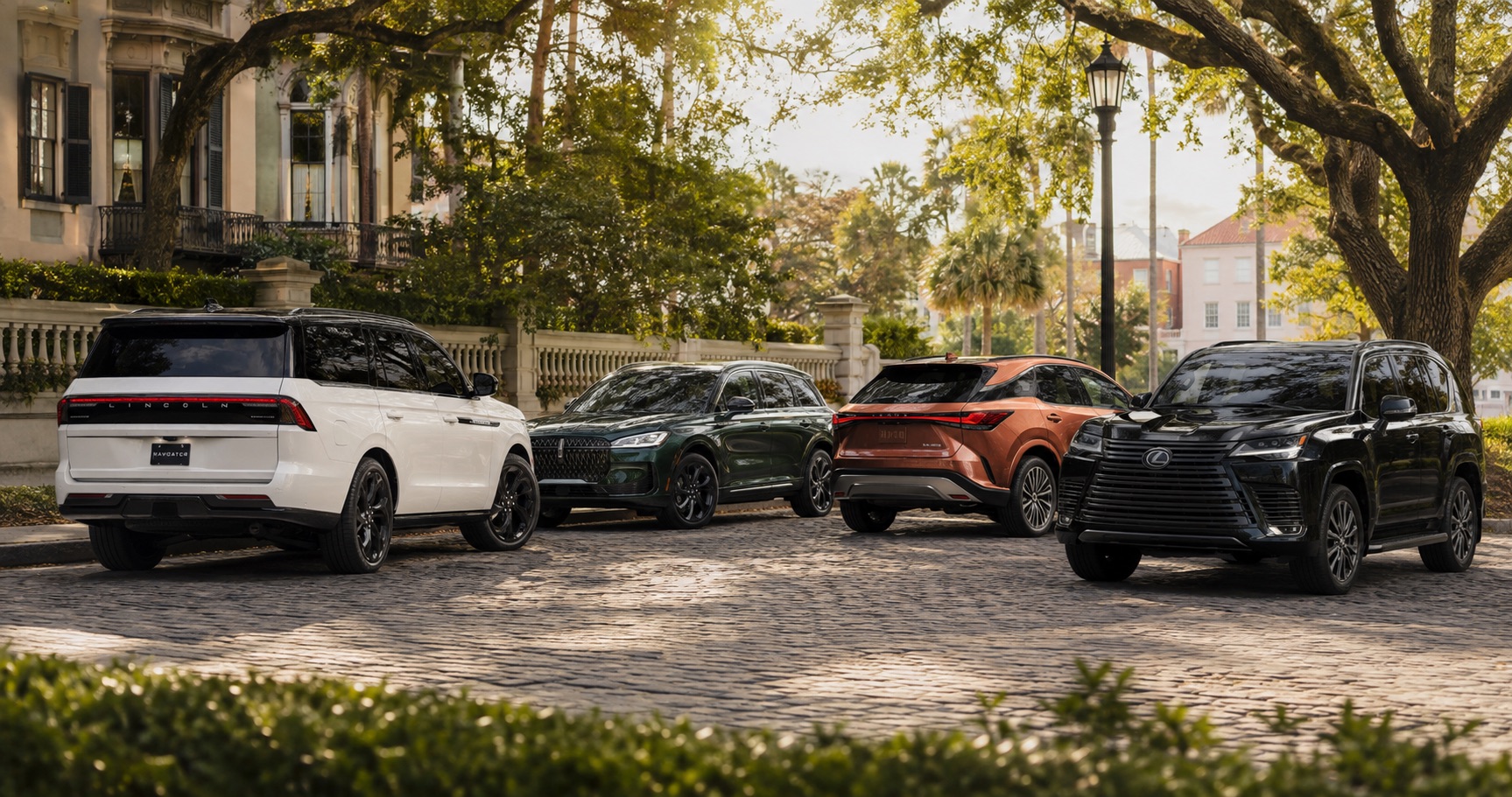 Four Lincoln and Lexus SUVs parked on a cobblestone street under large trees with historic homes in the background.
