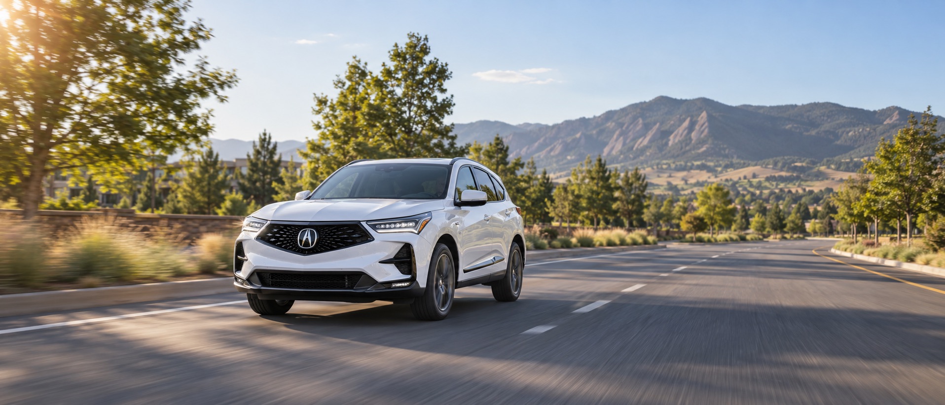 White Acura RDX driving through Boulder, Colorado with the Flatirons in the background