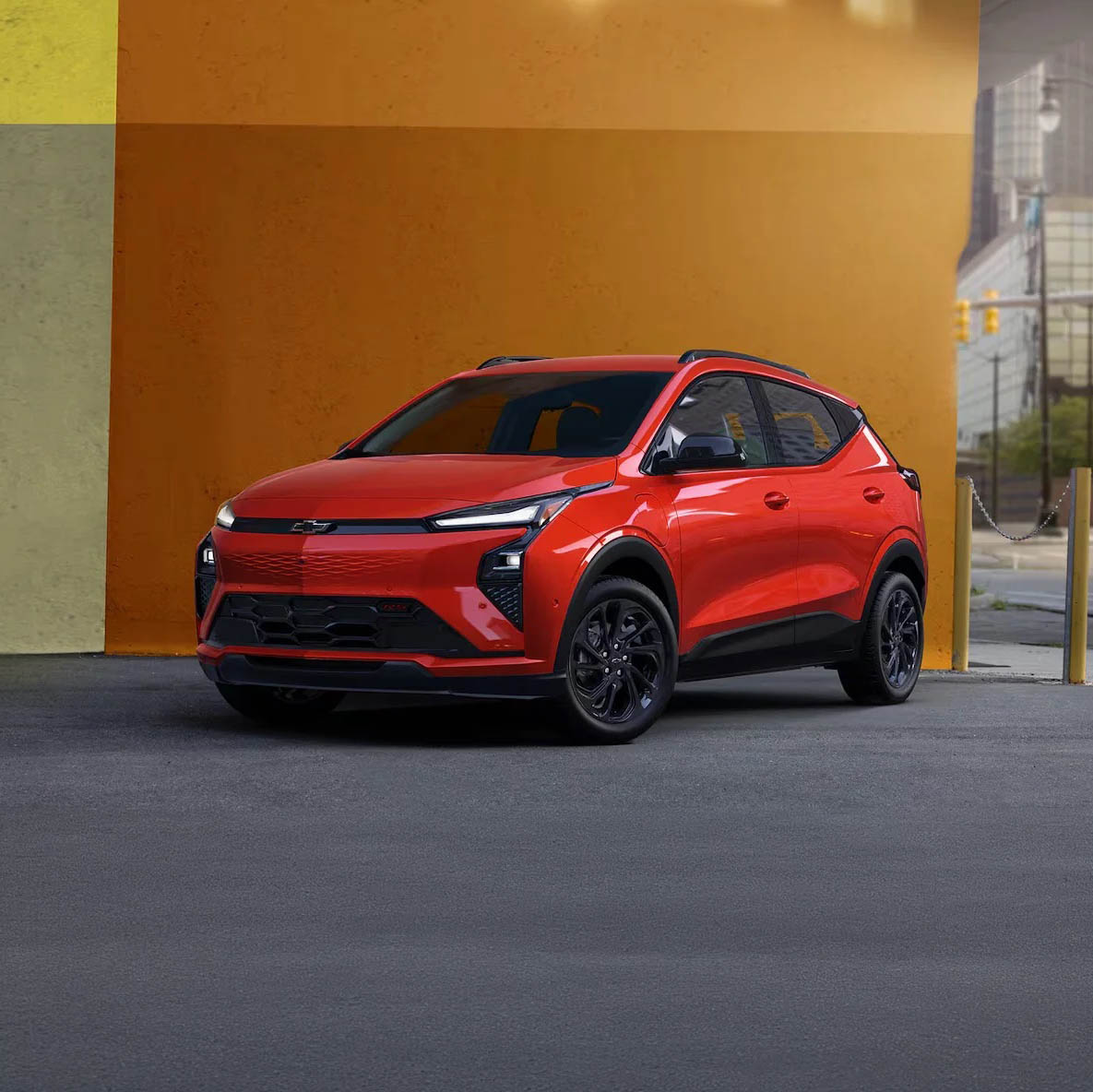 Red 2027 Chevrolet Bolt RS parked against a modern mural in the city