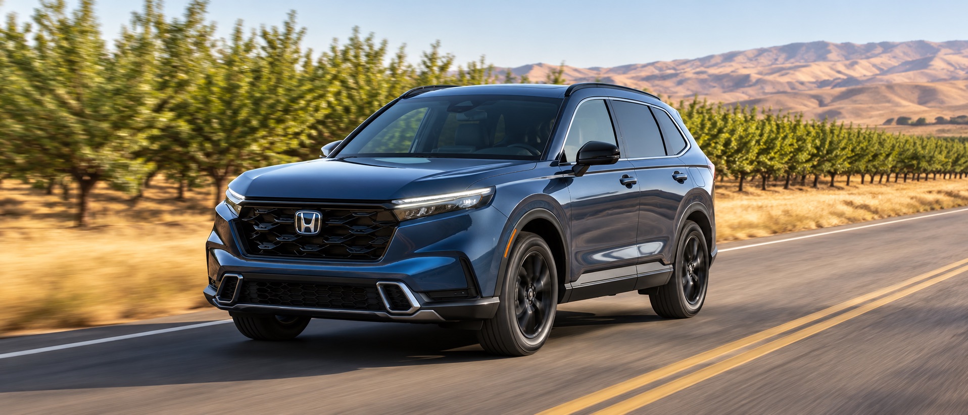 Blue 2027 Honda CR-V Sport Touring Hybrid driving past almond orchards and golden foothills near Tracy, California