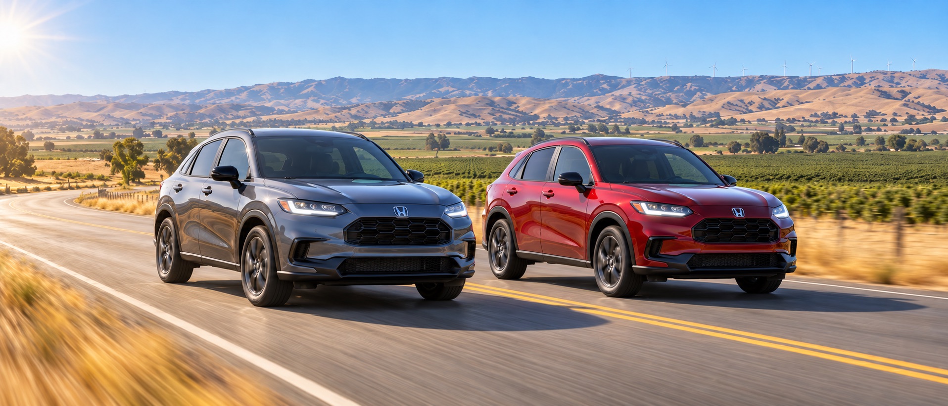 Two 2027 Honda HR-V Sport SUVs, one FWD and one AWD, driving on a scenic roadway near Tracy, California, with agricultural fields, dry summer grasses, Altamont foothills, and distant wind turbines in the background.
